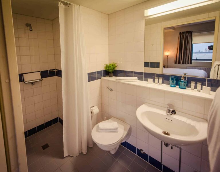 spacious bathroom with shower, toilet, sink and mirror.