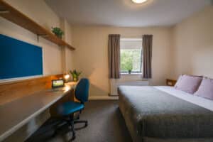 Simple bedroom with single bed, desk, and chair.