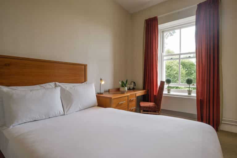 Bedroom with two single beds, desk, and window view.